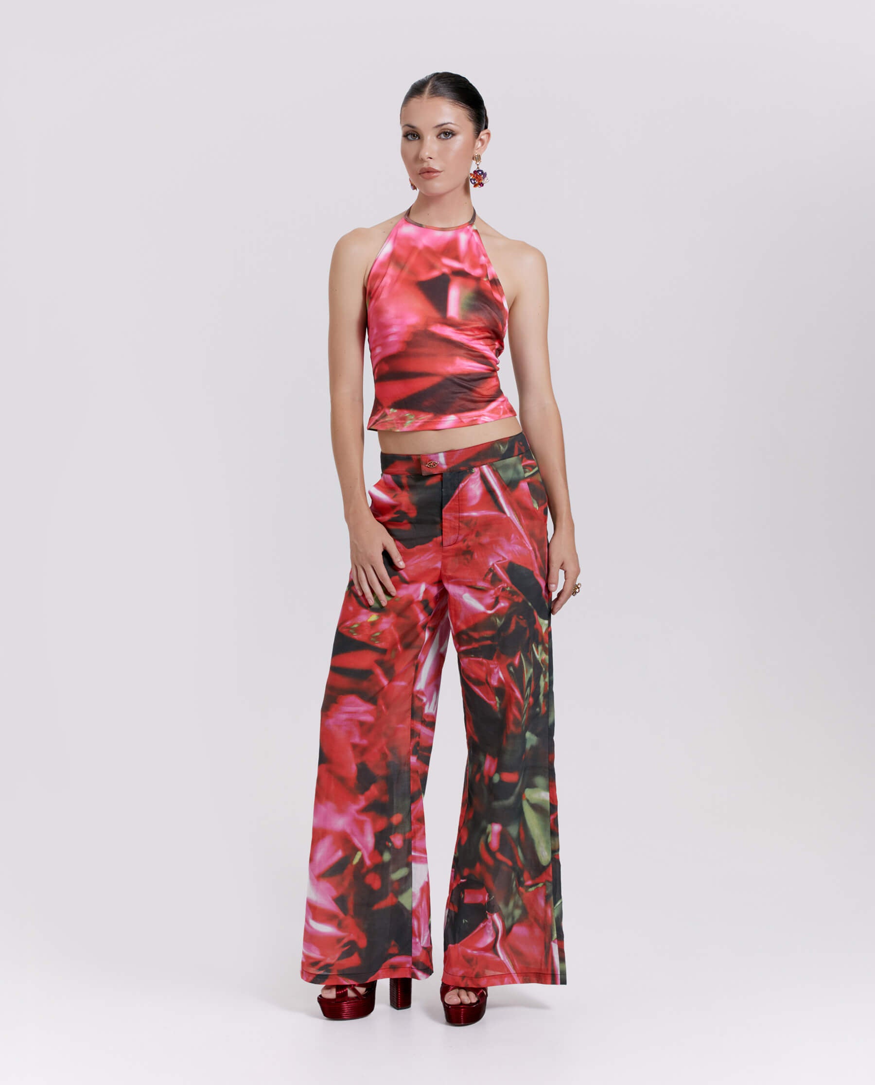 A vibrant, abstract pink and green patterned top with a halterneck tie fastening and open back, paired with matching pants.